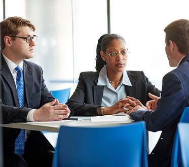 group of professionals wearing suits talks around a table