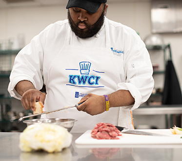 chef in kitchen wearing KWCI apron
