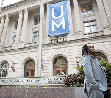 male student walking outside of law building
