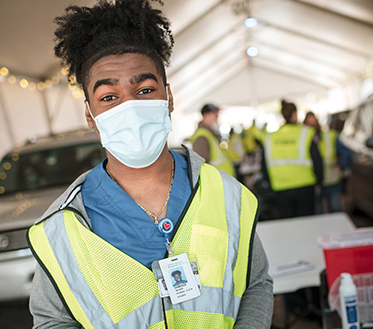 student wearing mask volunteering at vaccine site