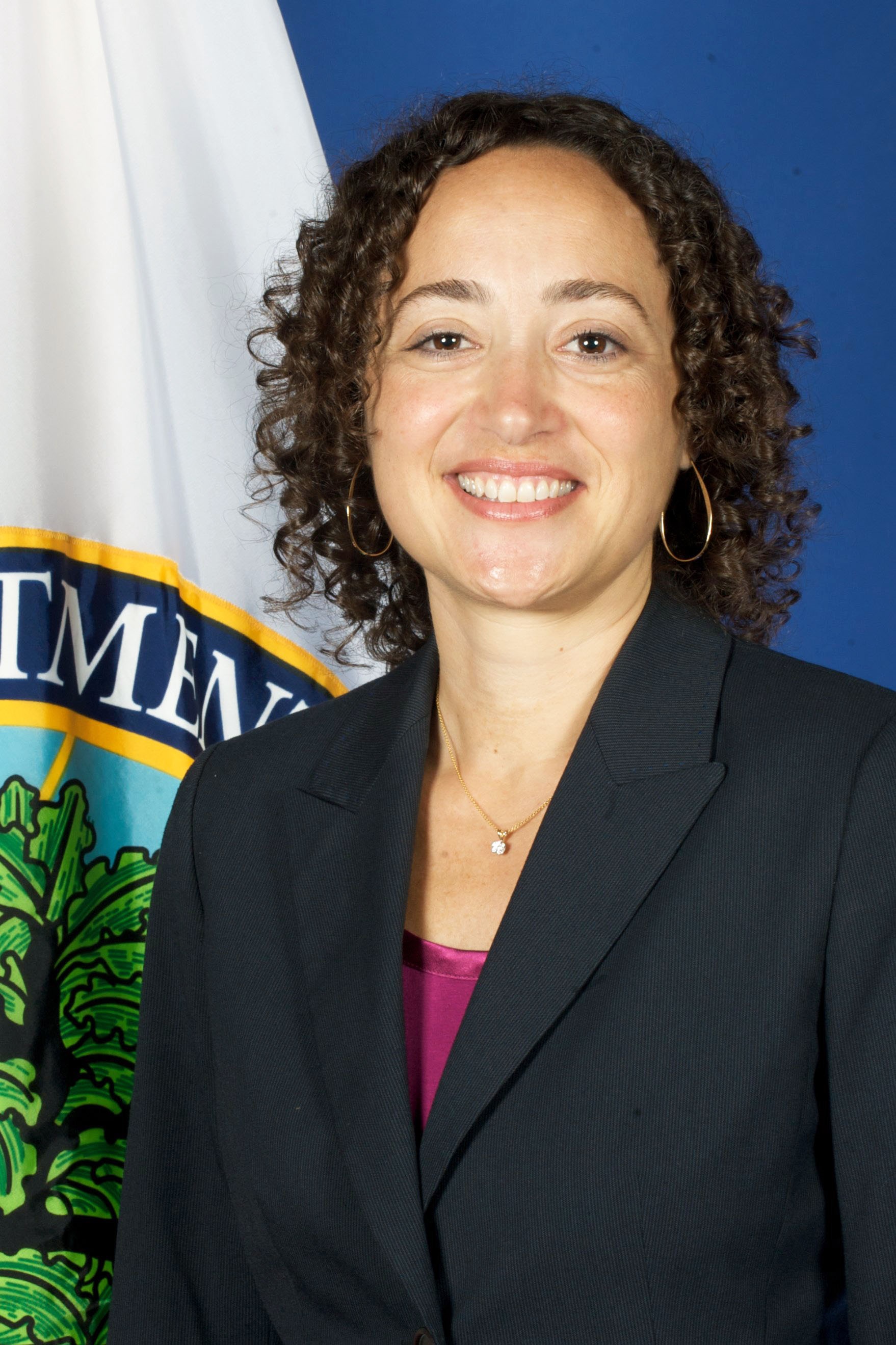 Catherine Lharmon smiles in front of a flag.