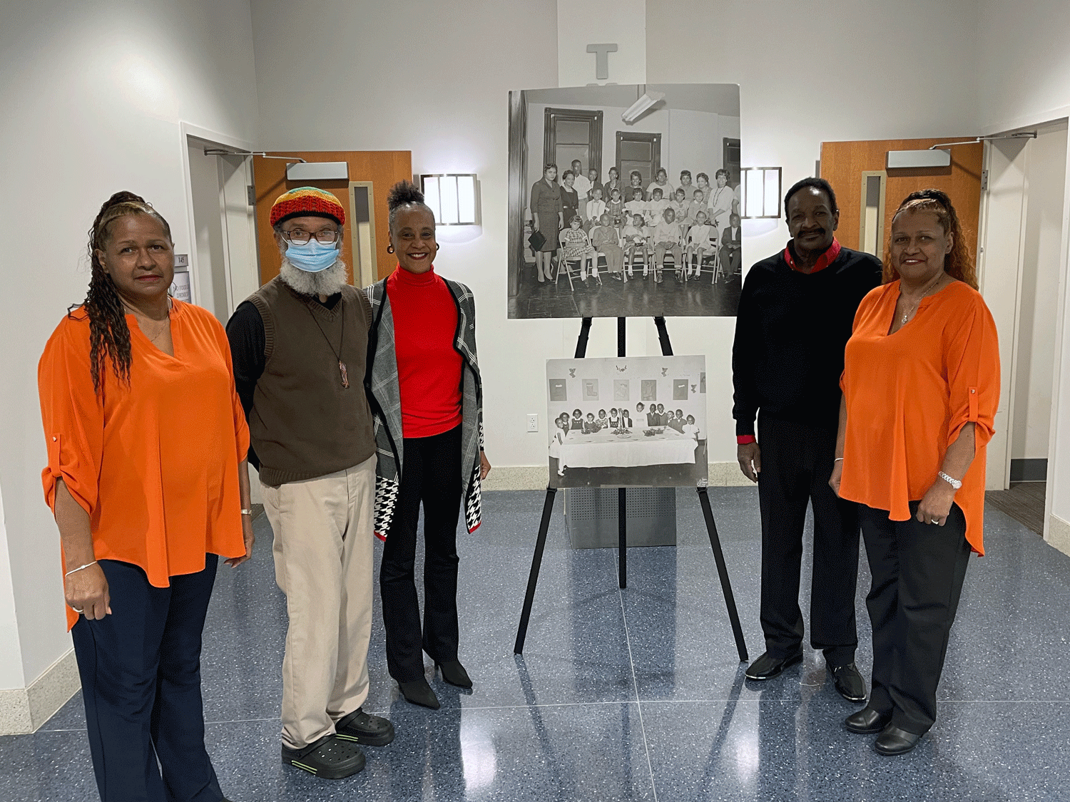 Five members of the Memphis 13 stand next to photos of their younger selves.