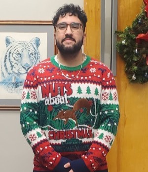 Pavel Qaladize wearing his "ugly sweater" featuring the squirrel from National Lampoon's Christmas Vacation in a Christmas tree