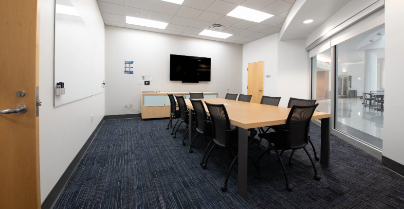 Photo of Conference Room 208 showing the table, whiteboard, and TV screen