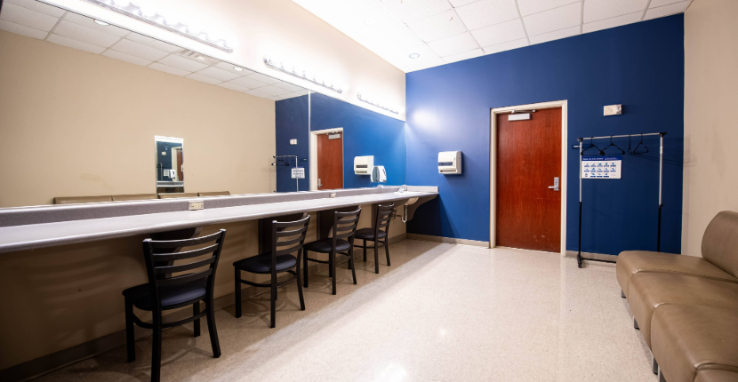 Rose Theatre dressing room with couch, several chairs and large mirror with bright lighting