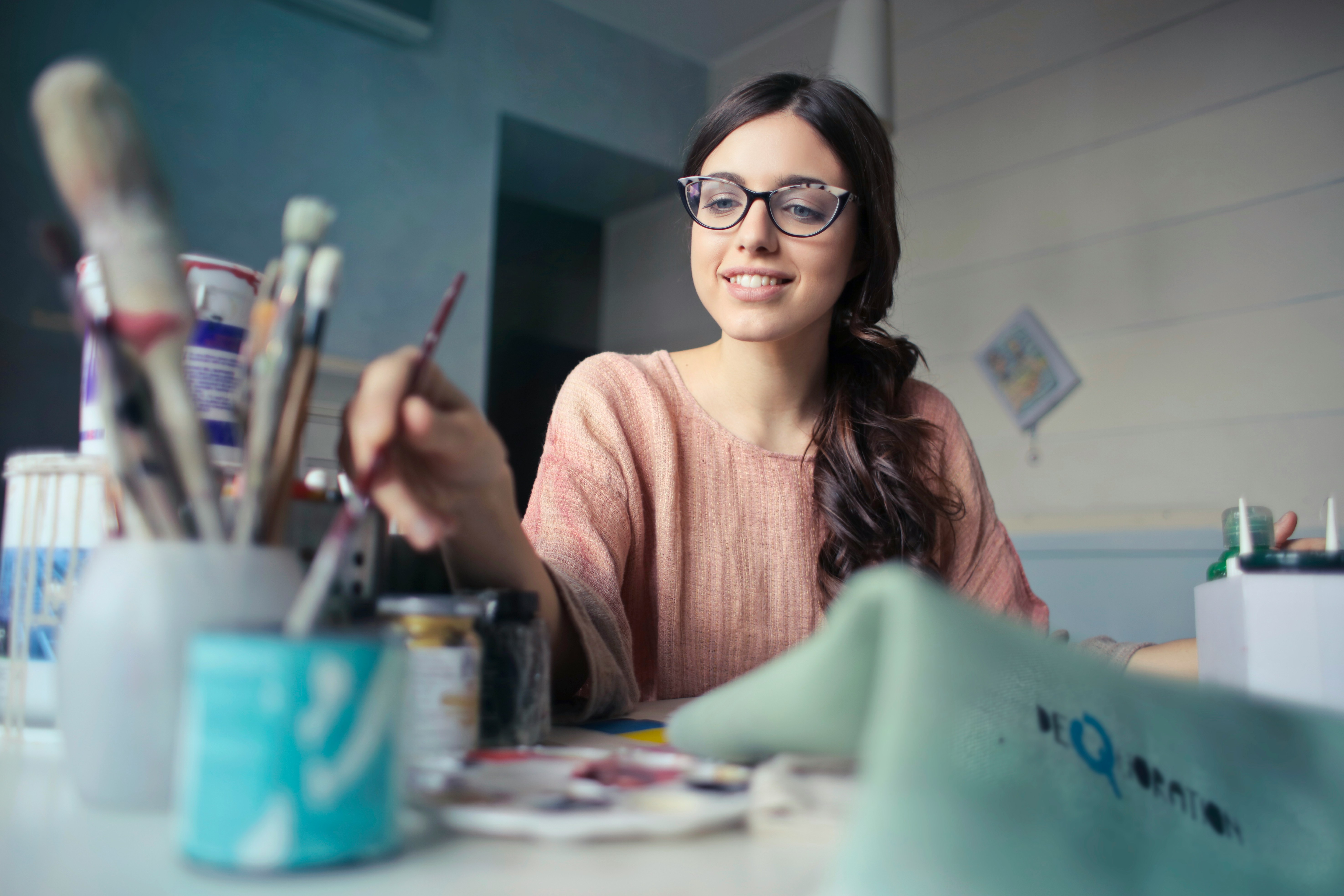 Woman artist organizing supplies and brushes at her desk.