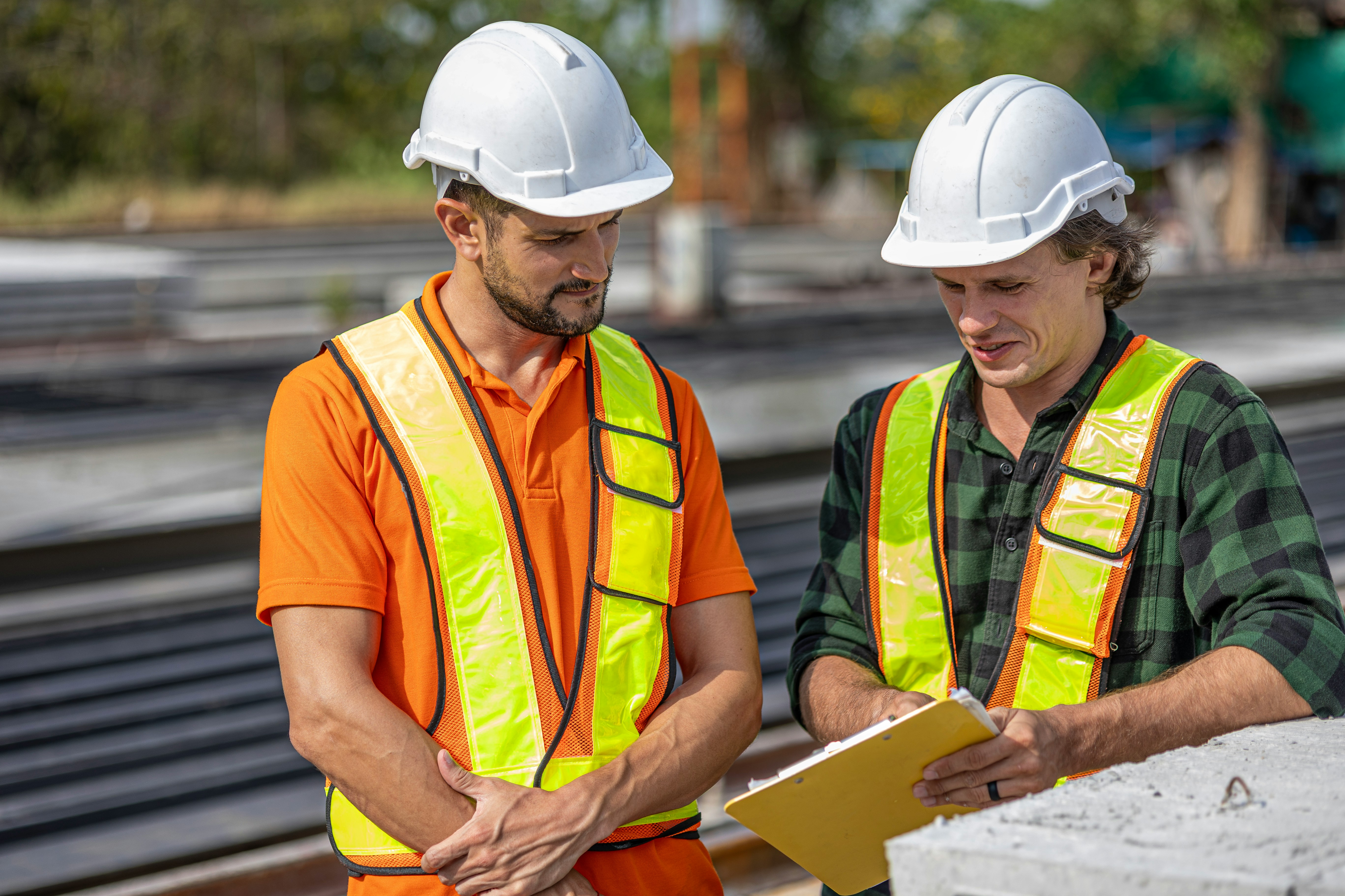 Two men talking over blueprints at a construction site