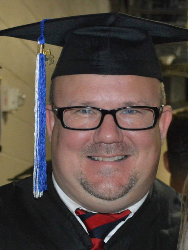 John smiles at commencement with his cap on