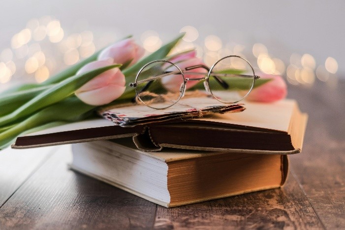 Image of glasses, books, and flowers