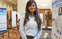 student participating in previous in-person SRF with poster behind her