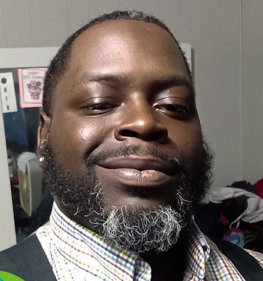 Photo of Richard Cooper, black man wearing a striped shirt and smiling proudly