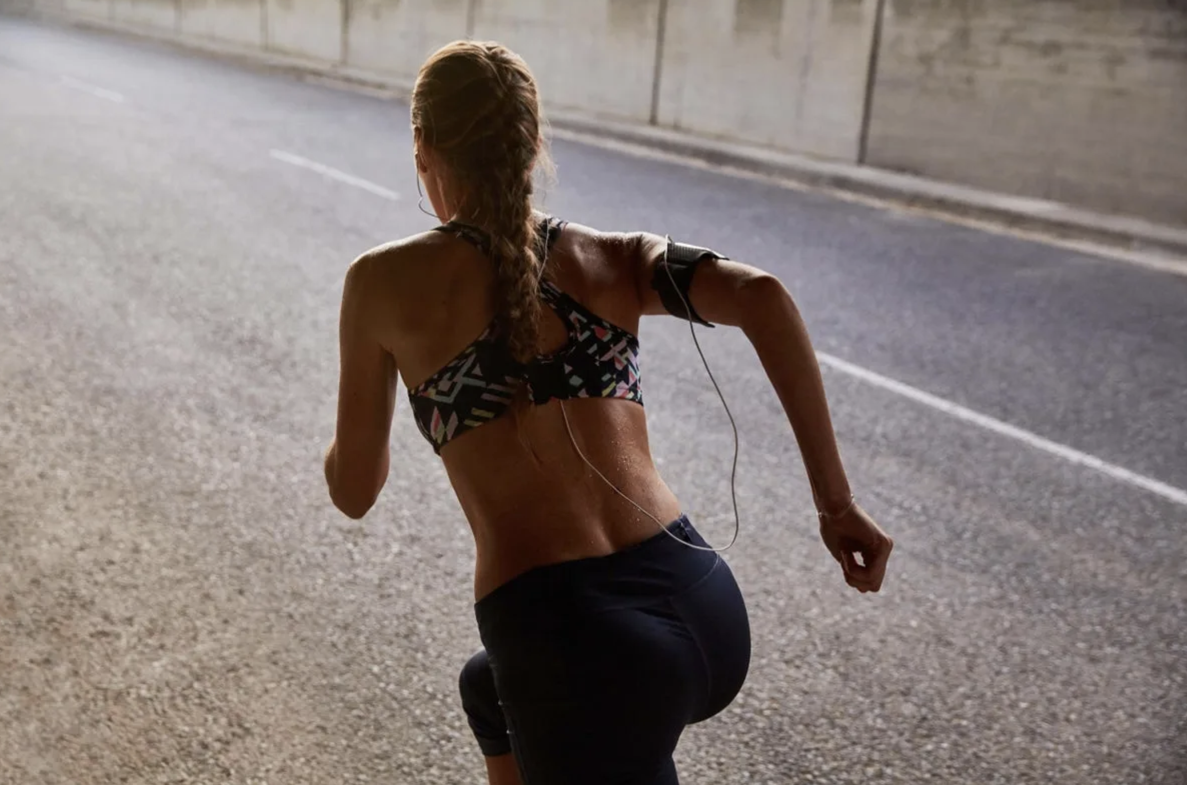 New research suggests wearing the right sports bra may increase your running performance Woman running in a sports bra and shorts