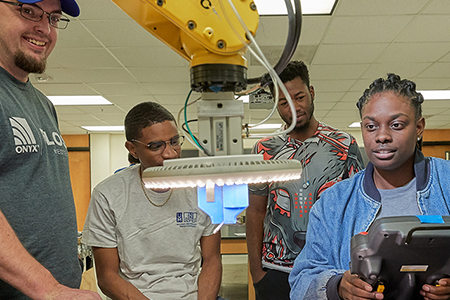 students in lab working with robot arm
