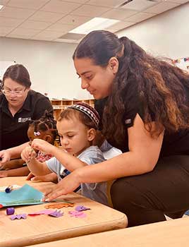 Two PM Ready staff members work with two children at a table