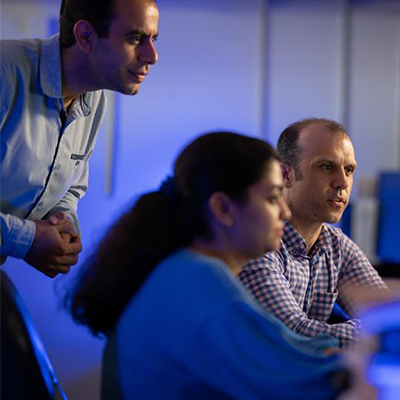 Three researchers reviewing data on a computer screen