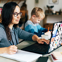 mother working on laptop next to child