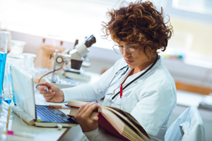 female researcher with book and microscope