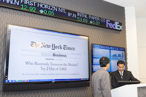 Two men in suits giving a financial presentation with digital screens