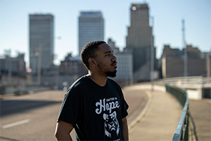 man standing on street with city buildings in the background