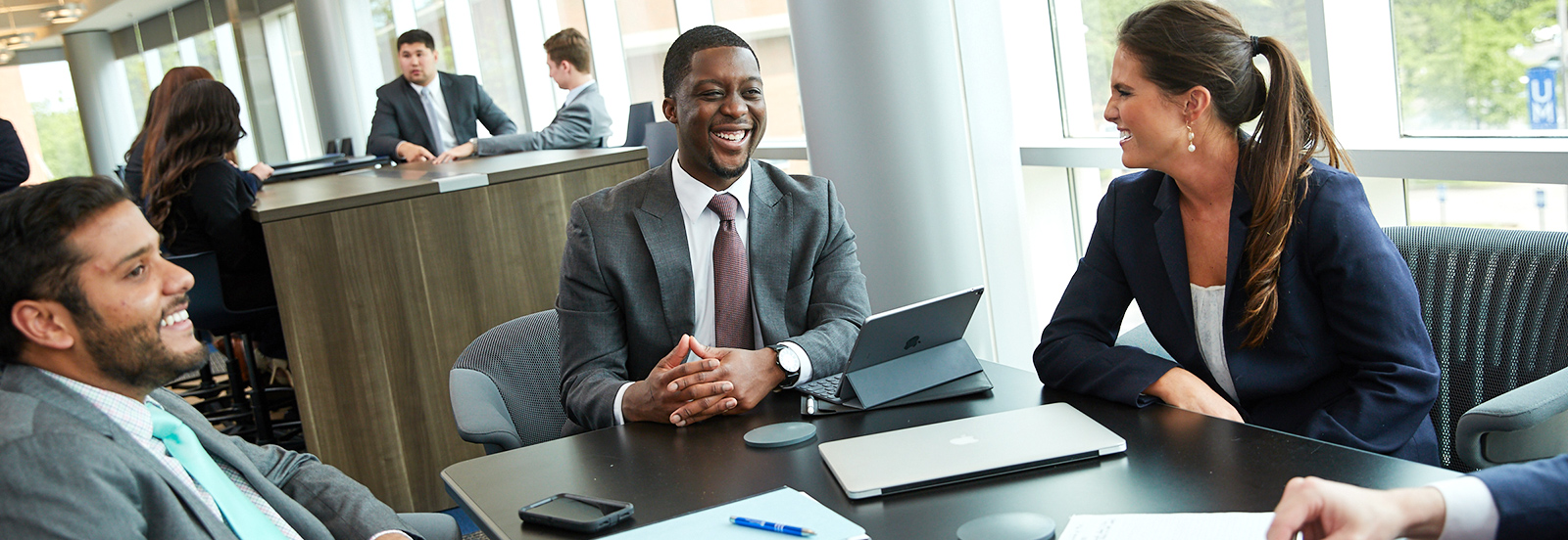 group of professional students sitting around table with laptop and talking and laughing