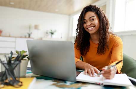Student studying with computer and taking notes