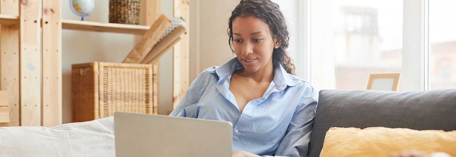 female working on laptop in her lap while sitting on a couch