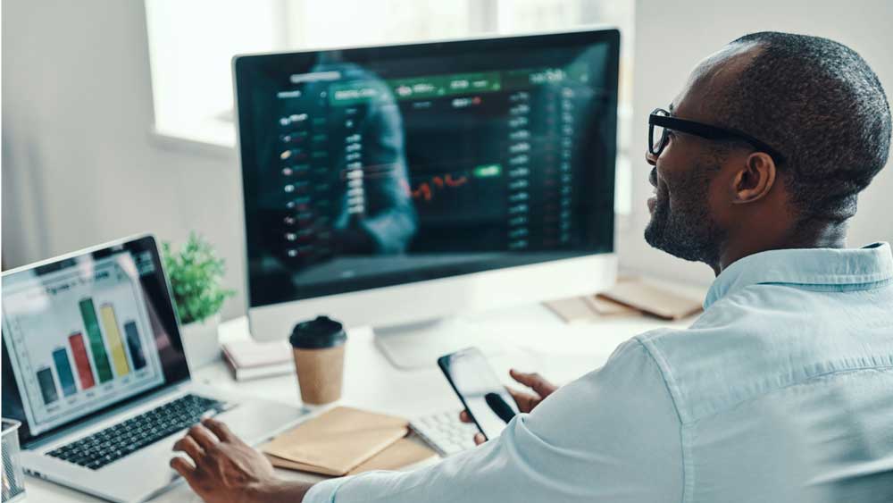 uofm global student working on reports on laptop at desk