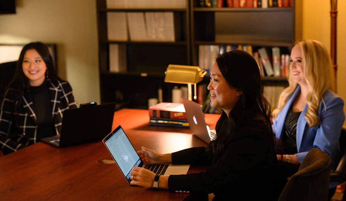 Three female law students sitting at table in law library